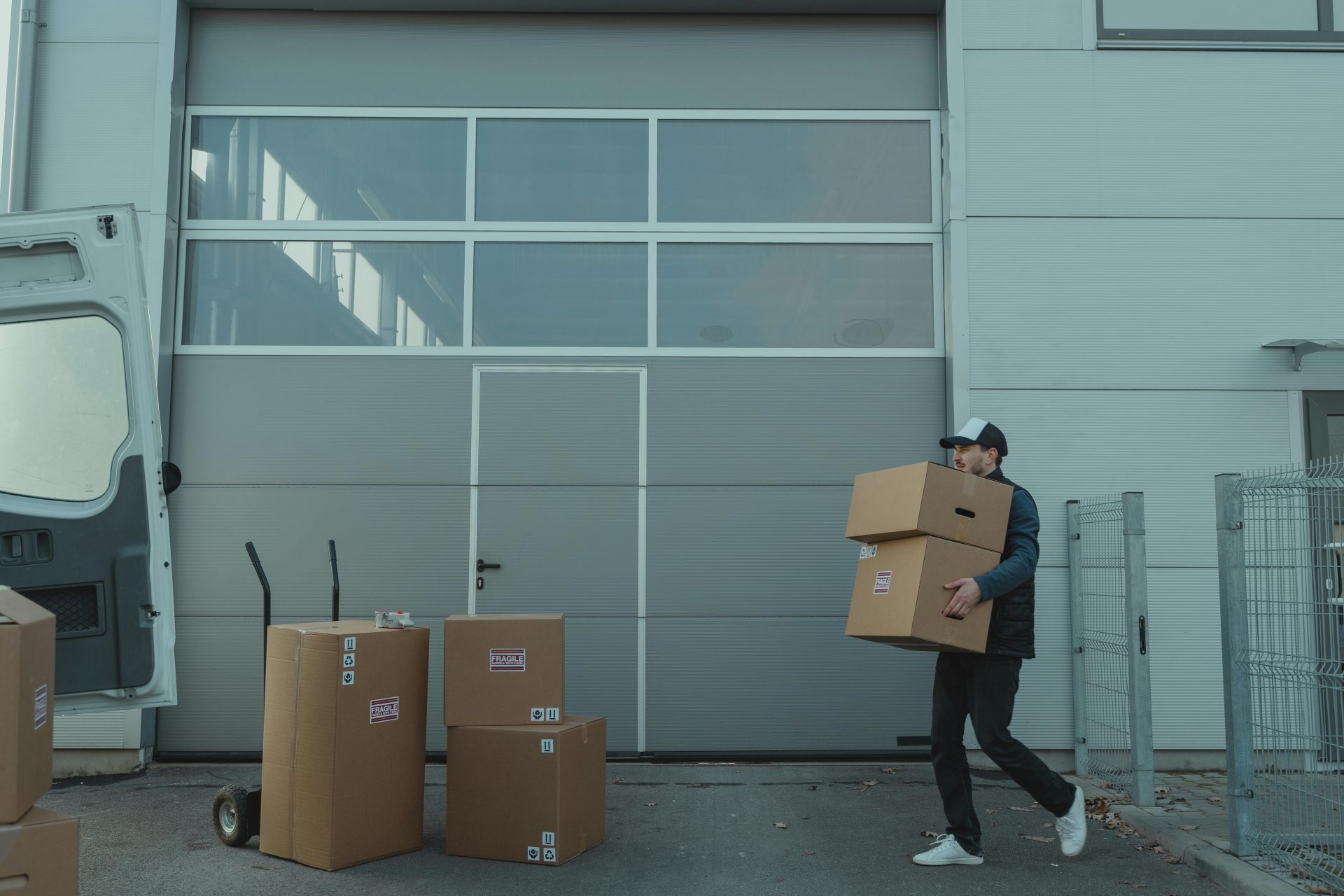Un repartidor transportando cajas de cartón fuera de un almacén.