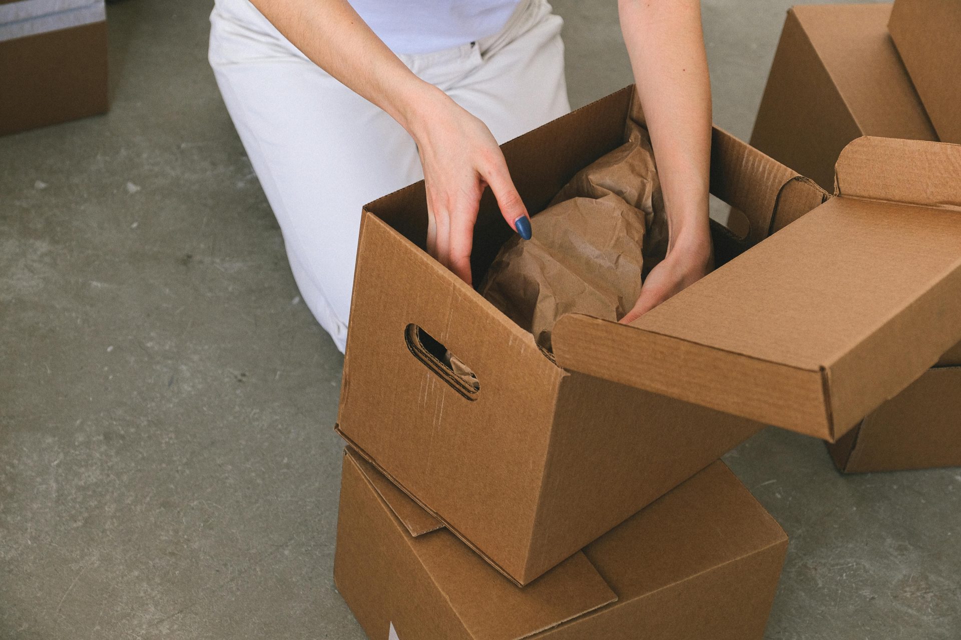 Una mujer organizando cajas de cartón mientras se prepara para mudarse a un nuevo apartamento.