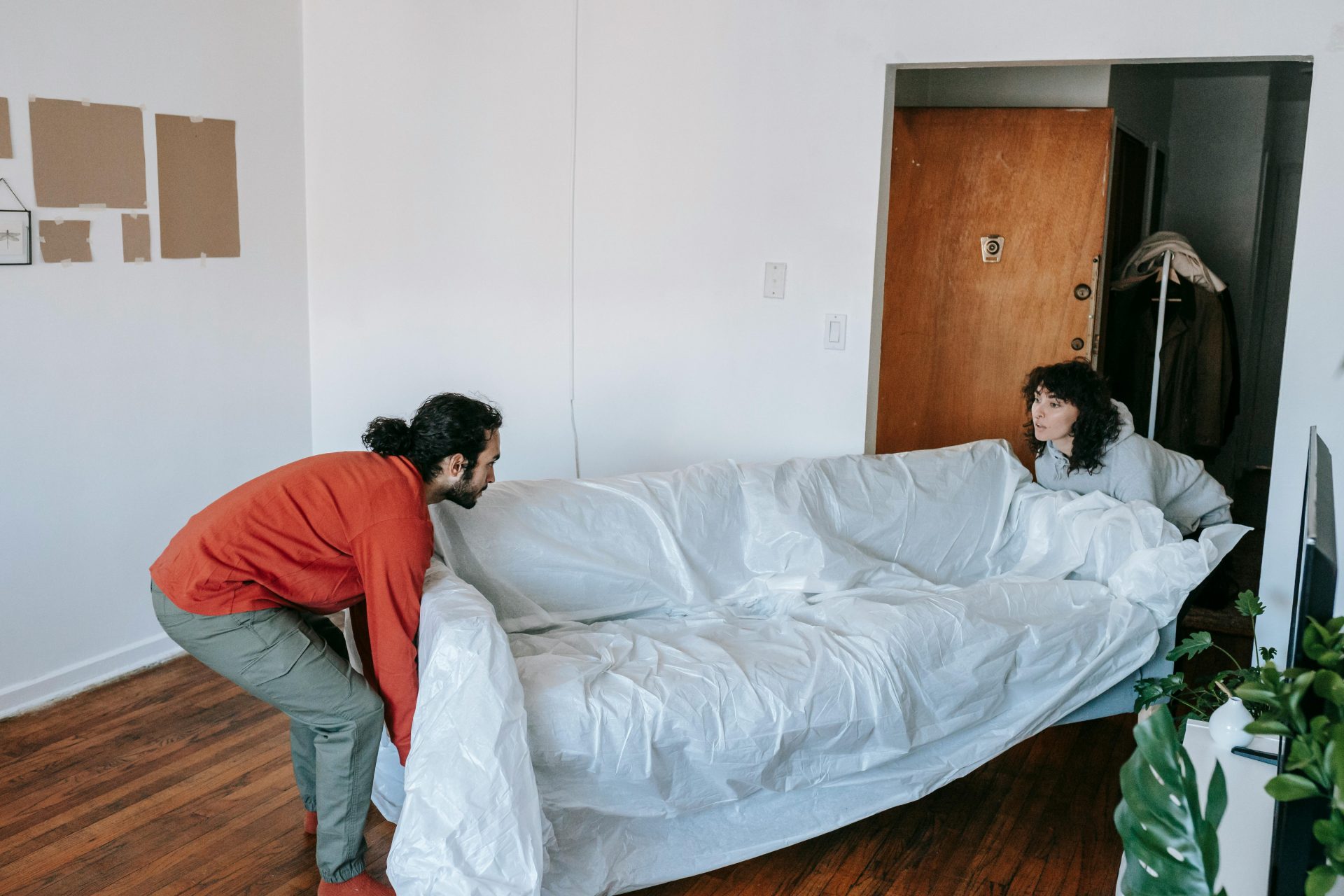 Una pareja ayuda a levantar un sofá mientras se mudan a un nuevo apartamento.