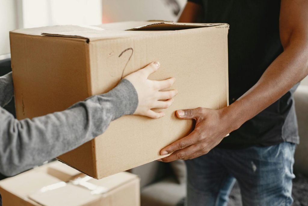Primer plano de dos personas pasándose una caja de cartón en un espacio interior.